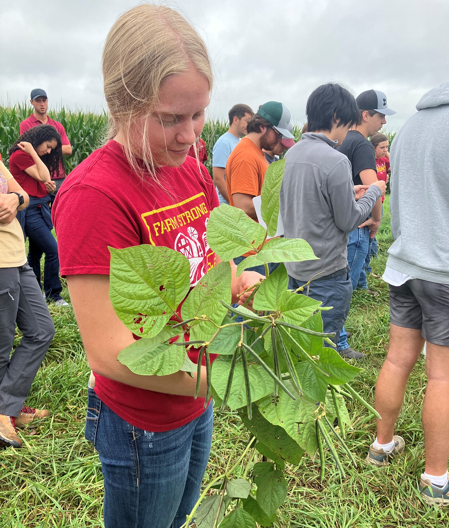 December McGrew with a mung bean plant at the AEA Farm